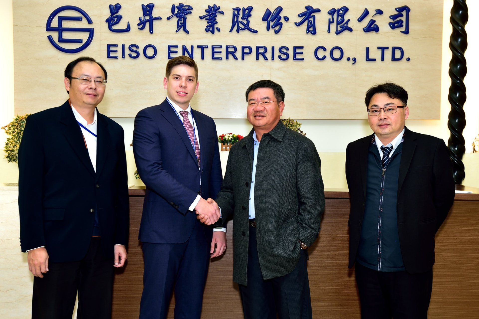 Handshake at EISO Enterprise Co., Ltd. beneath the company signage